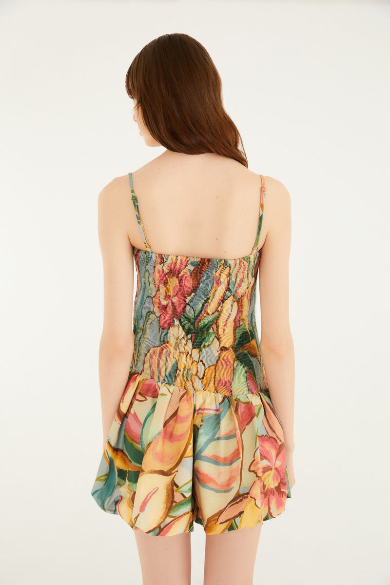 Vista trasera del vestido corto con estampado de follaje colorido, destacando el diseño de la espalda.
