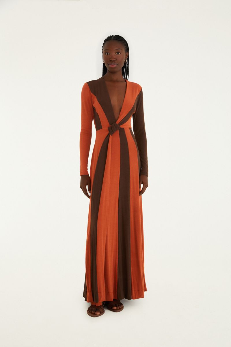 Vestido largo con escote profundo en V, con estampado geométrico en tonos de marrón y naranja, visto de frente.
