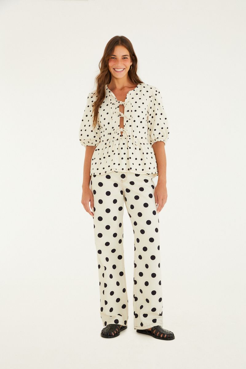 Imagen de una modelo vistiendo un pantalón recto de sarga con estampado de lunares y blusa combinada.