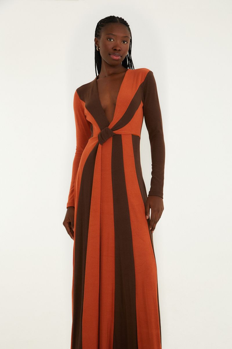 Vestido largo con estampado geométrico en tonos de marrón y naranja, visto de lado.