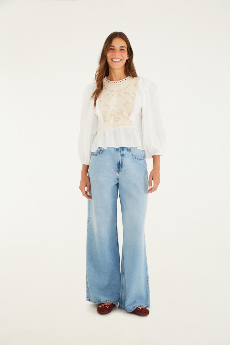 Imagen de una modelo vistiendo un pantalón jeans maxi wide azul claro con blusa blanca de encaje.
