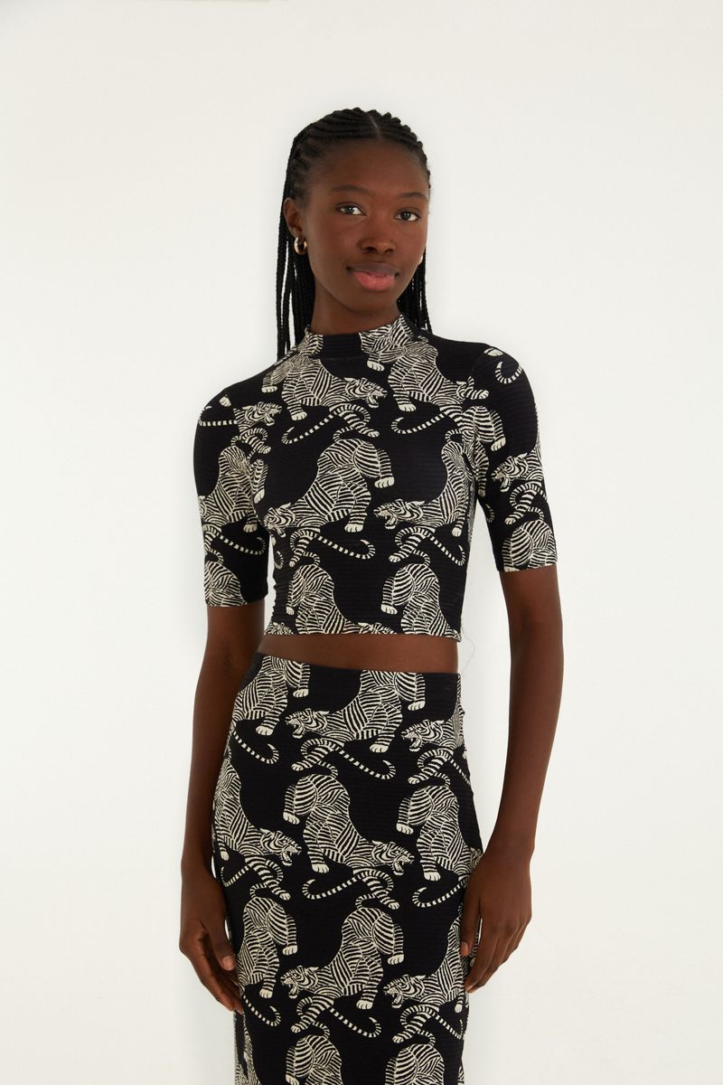 Blusa cropped con estampado de tigres sobre fondo negro, vista frontal.