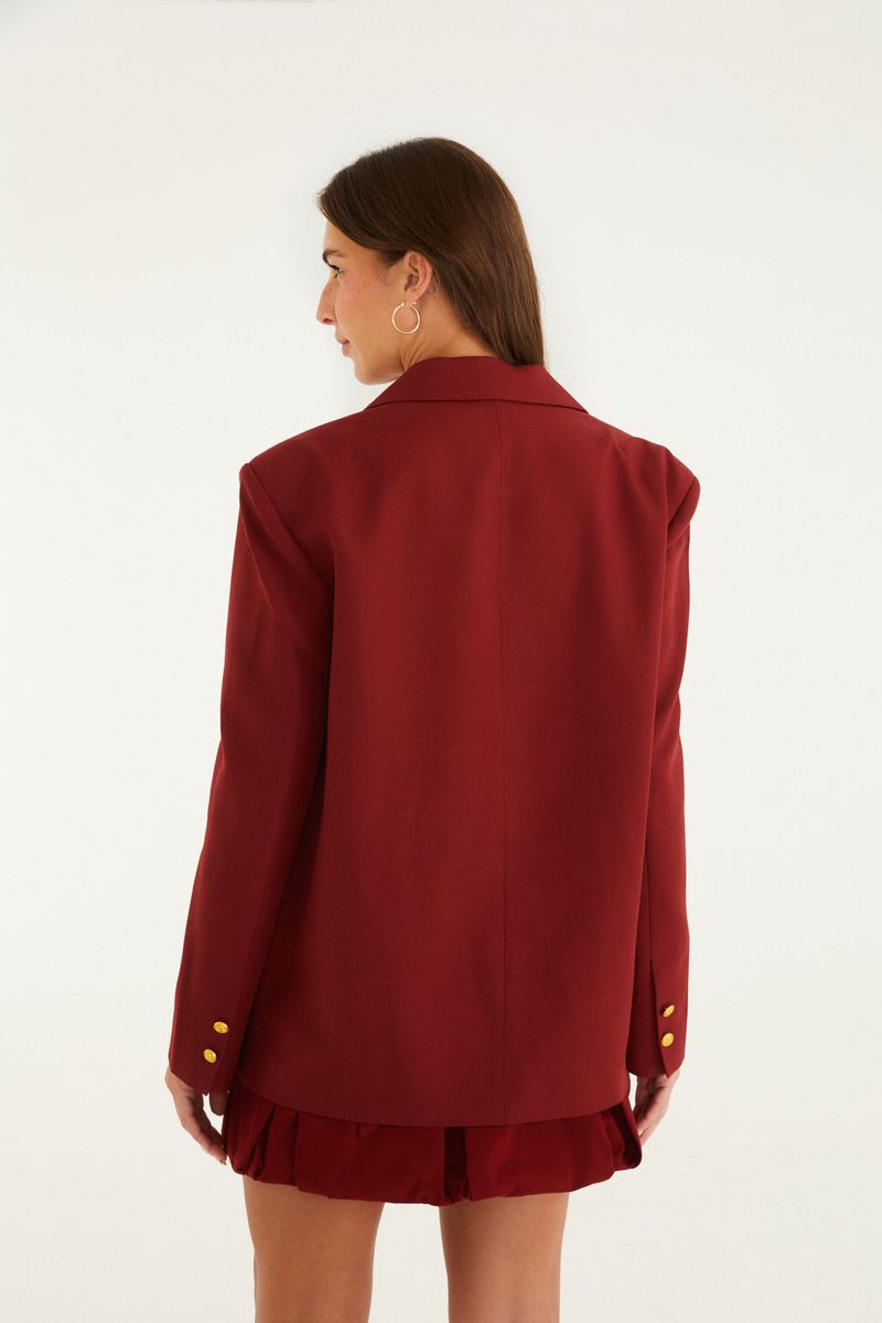 Vista trasera del blazer rojo de corte sastre, mostrando el diseño estructurado.
