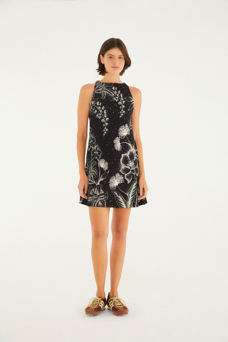 Vestido corto negro con estampado floral blanco, visto de espaldas.