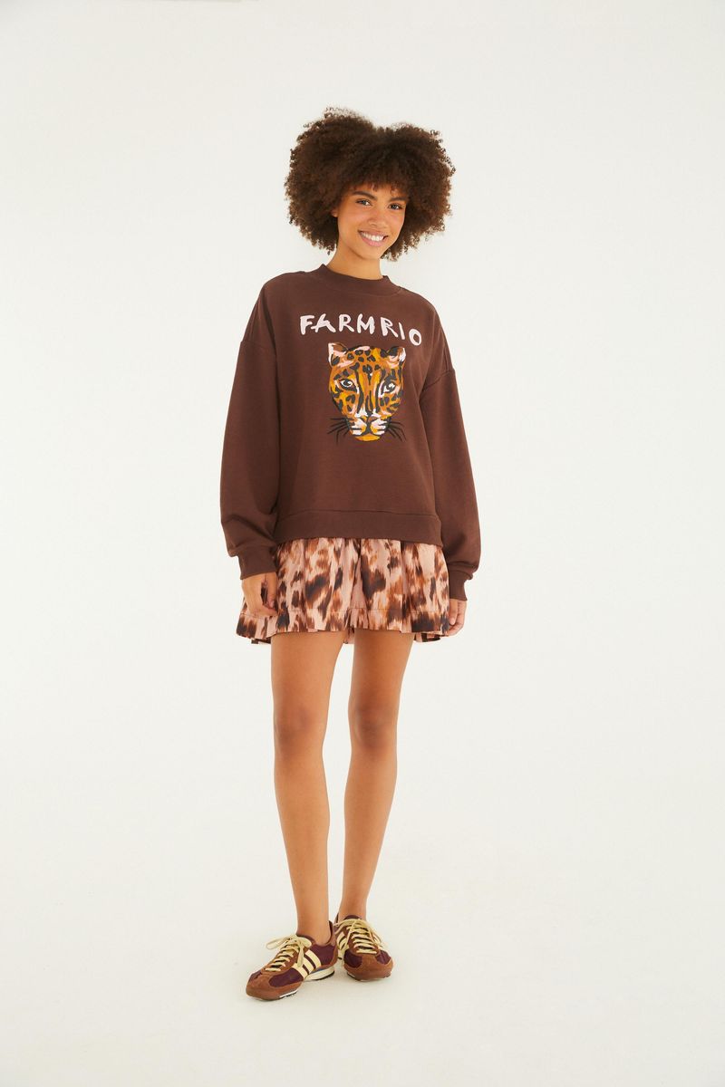 Modelo usando un vestido de moletón marrón con estampado de tigre y texto 'Farm Rio', combinado con falda estampada.