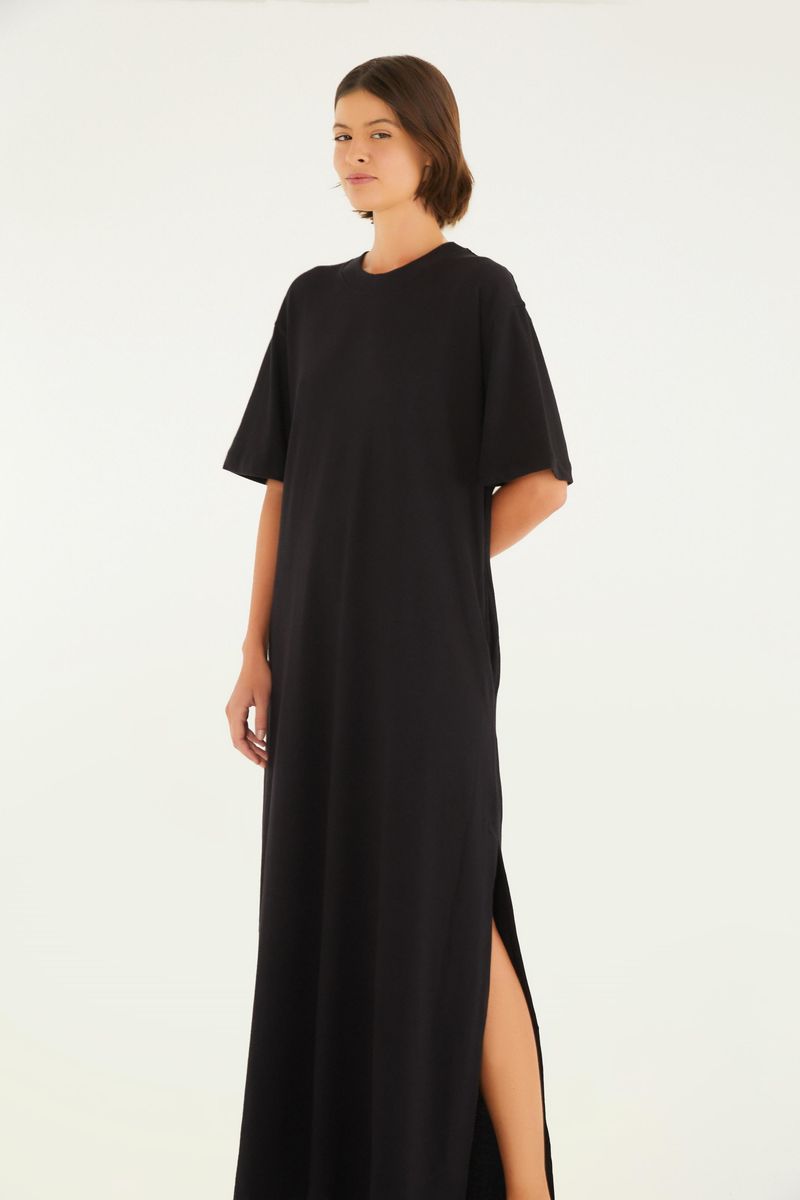 Vestido negro estilo camiseta con abertura lateral, exhibido en una pose lateral mostrando la apertura.