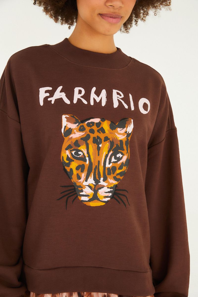 Acercamiento del cuello del vestido de moletón marrón con estampado de tigre y texto 'Farm Rio'.