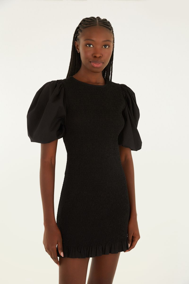 Vista trasera del vestido corto negro con botones decorativos en la parte superior.