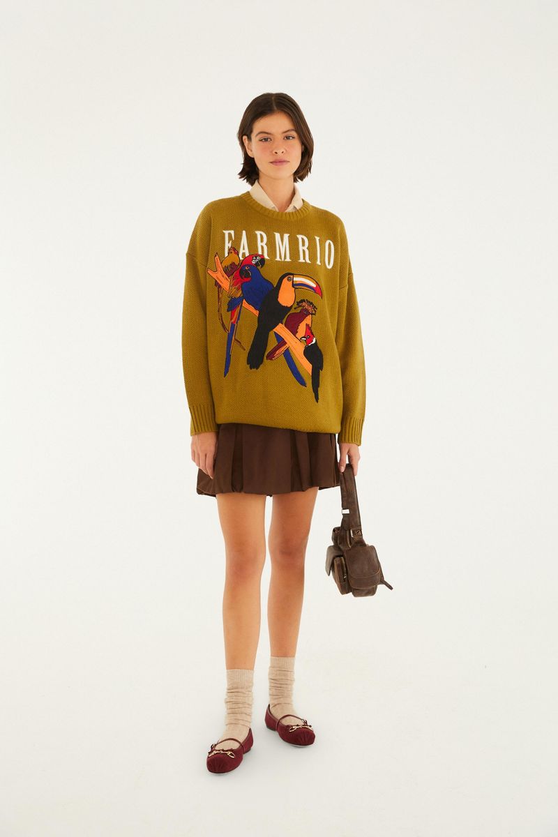 Modelo llevando un cardigan de tricot Farm Rio con estampado de tucanes y aves, combinado con falda y zapatos.