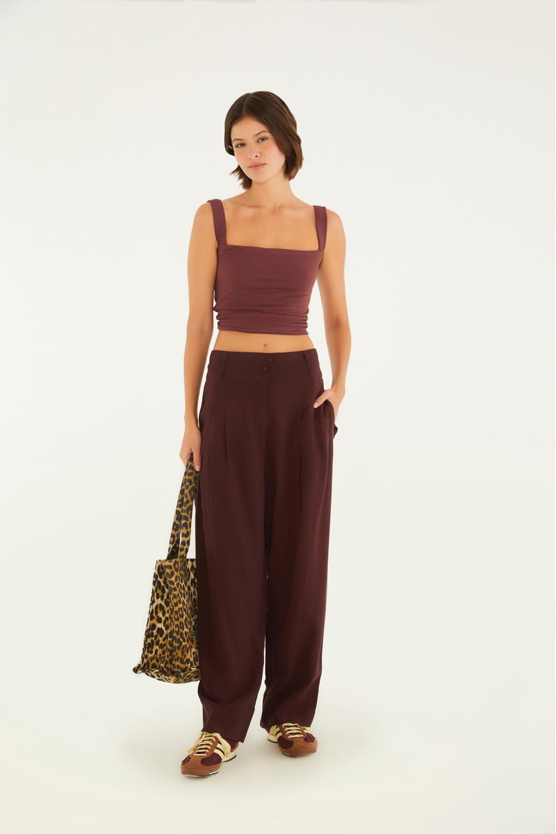 Conjunto con top recto fruncido y pantalón de cintura alta, complementado por bolso estampado.