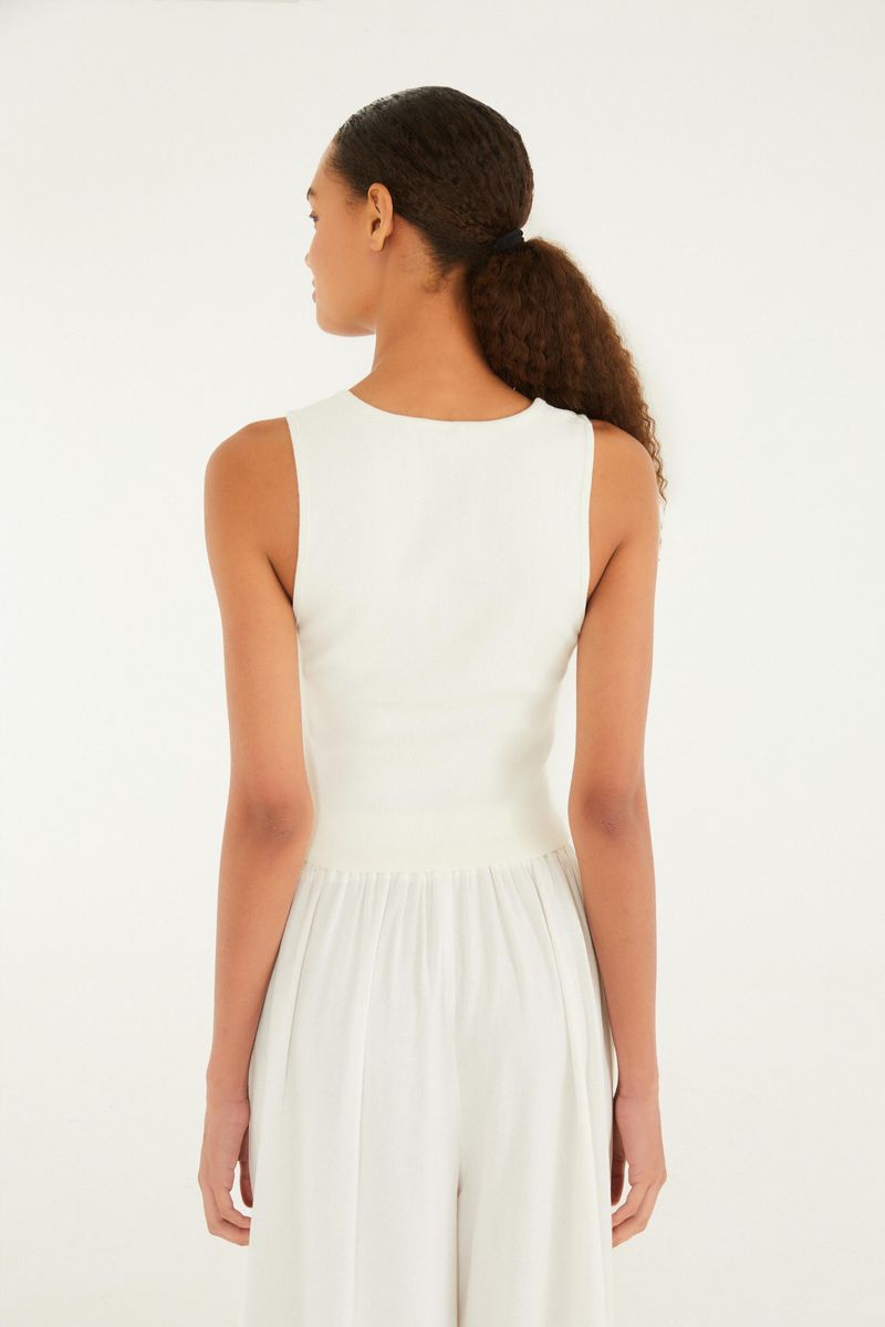 Imagen de una camiseta de tirantes estilo cropped blanca vista desde atrás, mostrando el corte recto y ajustado.