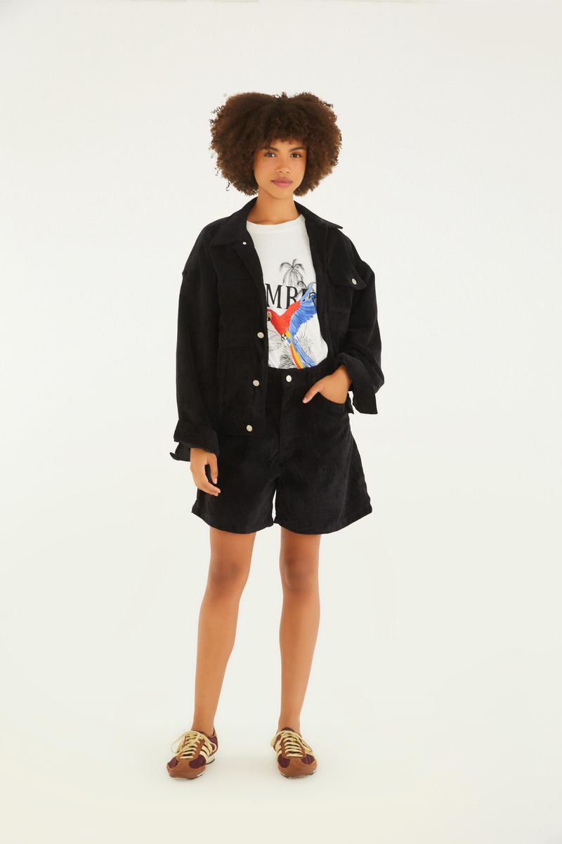 Modelo vistiendo la camiseta con shorts negros y chaqueta negra, vista completa.