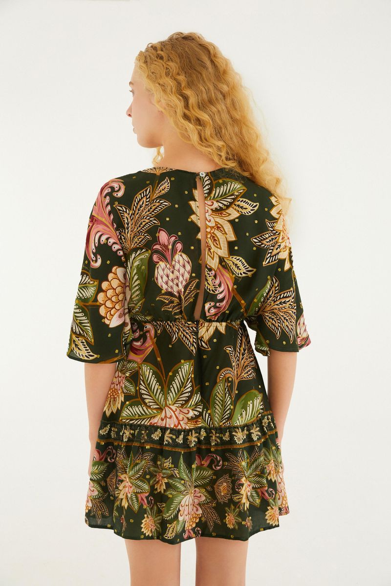 Vestido corto floral con mangas tres cuartos, visto desde atrás en modelo con cabello rubio.