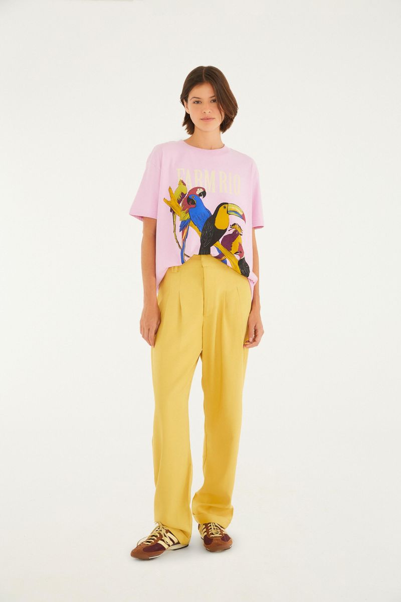Modelo usando pantalón zanahoria amarillo con camiseta rosa estampada, vista frontal.
