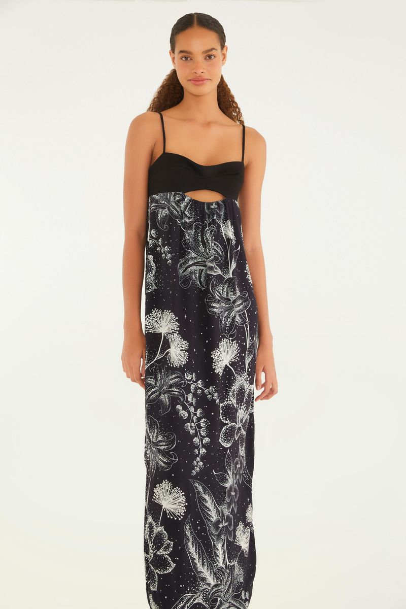 Vista trasera del vestido largo con tirantes finos, estampado floral en tonos oscuros y detalle recortado en la parte delantera.