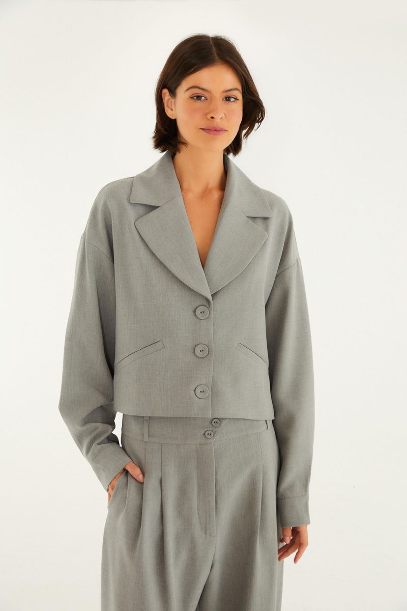 Blazer de alta costura en mezcla gris con solapa entallada y cierre de botones, visto de frente.