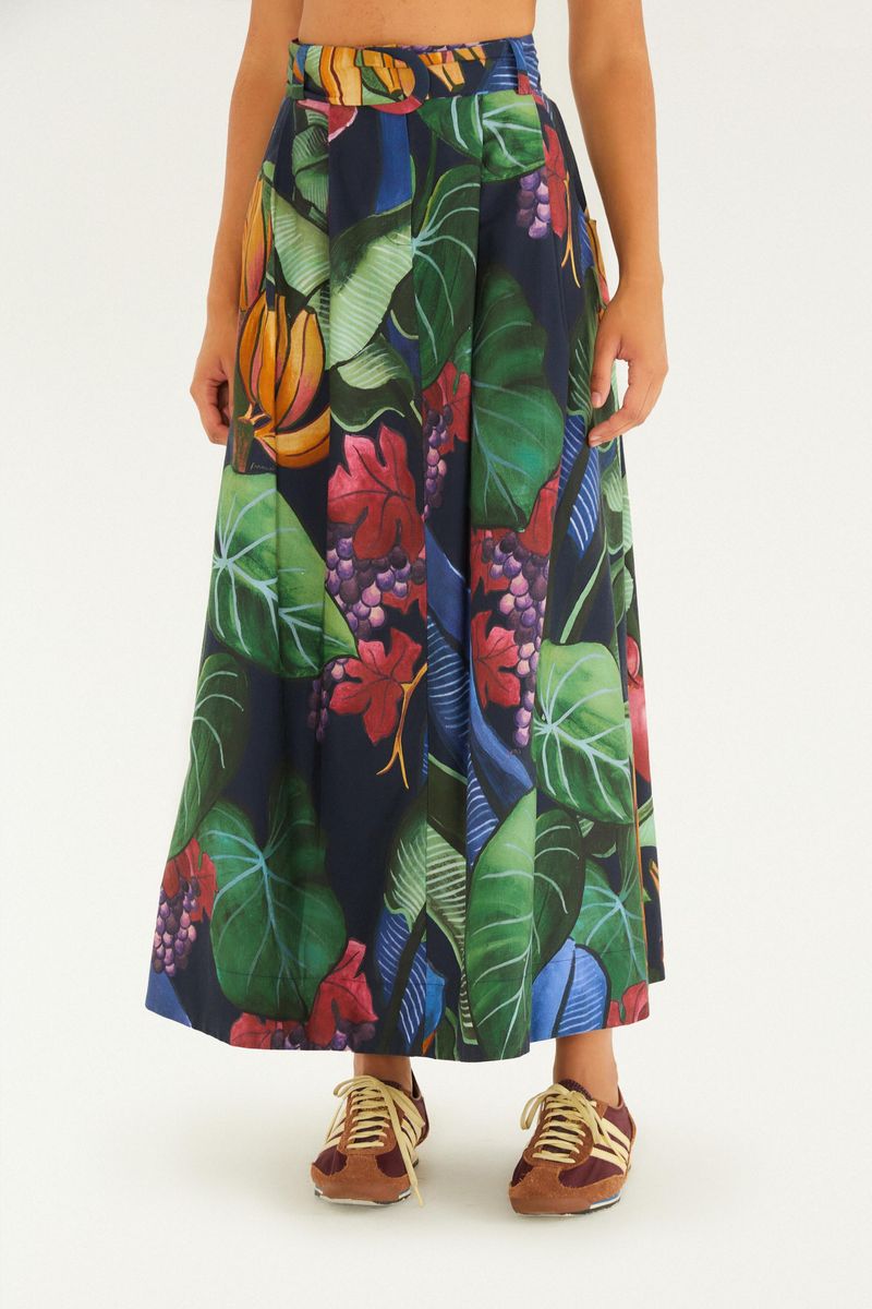 Detalle de la falda larga estampada con elementos tropicales y fondo azul oscuro, vista lateral.