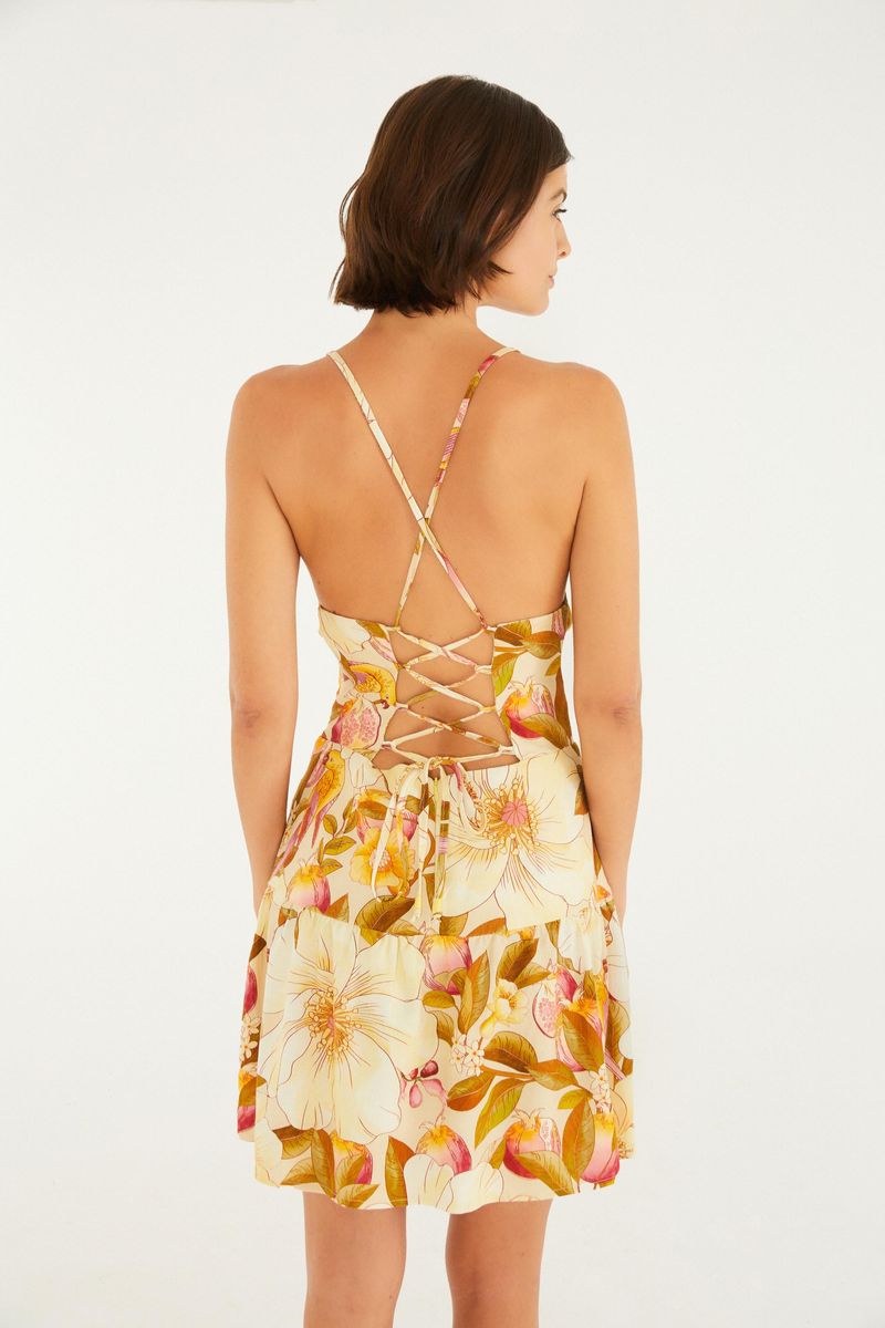 Primer plano de la espalda de un vestido corto con estampado floral, mostrando detalles cruzados y tiras finas.