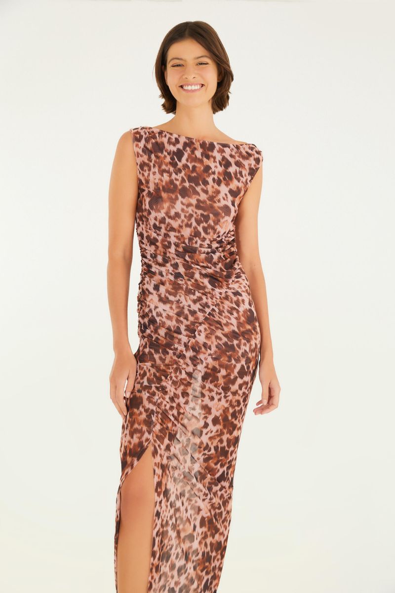 Imagen de un vestido largo con estampado de leopardo, visto de lado, destacando la abertura lateral y el ajuste al cuerpo.