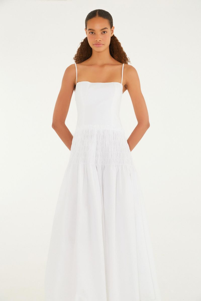Imagen de una modelo vistiendo un vestido largo blanco con tirantes finos, vista trasera.