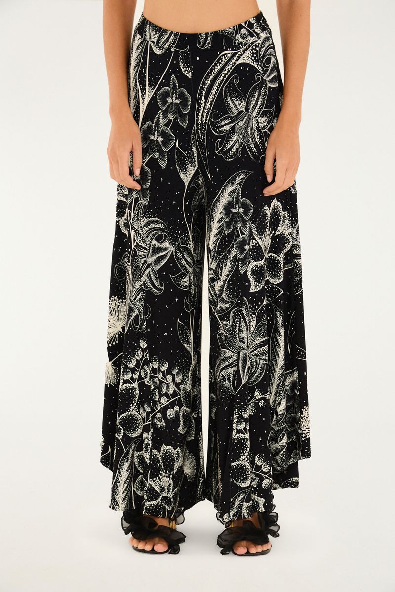 Imagen de un pantalón palazzo con estampado floral sobre fondo negro, vista lateral.