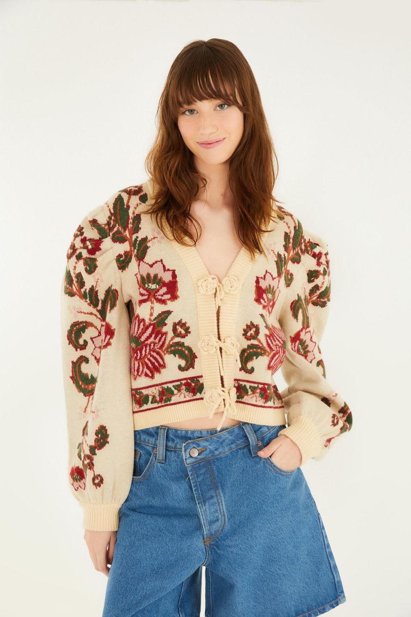 Cardigan corto de tricot con estampado floral visto de frente, destacando el cierre con botones y las mangas abullonadas.