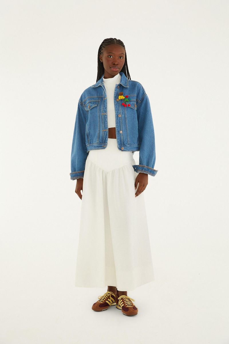 Modelo usando falda con rueda blanca, chaqueta de jean y tenis.
