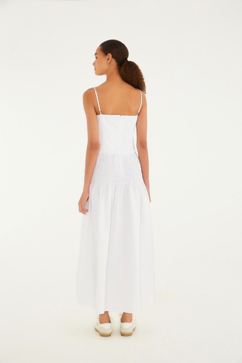 Imagen de una modelo vistiendo un vestido largo blanco con tirantes finos, vista lateral.