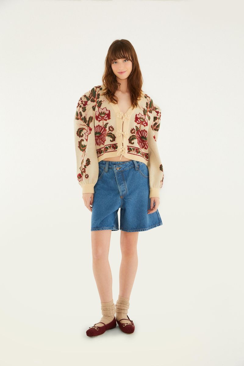 Modelo vistiendo el cardigan corto de tricot con estampado floral, combinado con shorts de mezclilla y zapatos bajos.