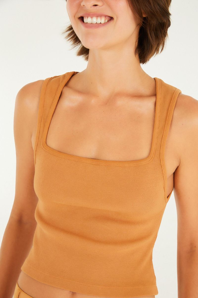 Imagen de una camiseta cropped en tono terracota, vista de cerca, destacando los detalles del tejido y acabados.