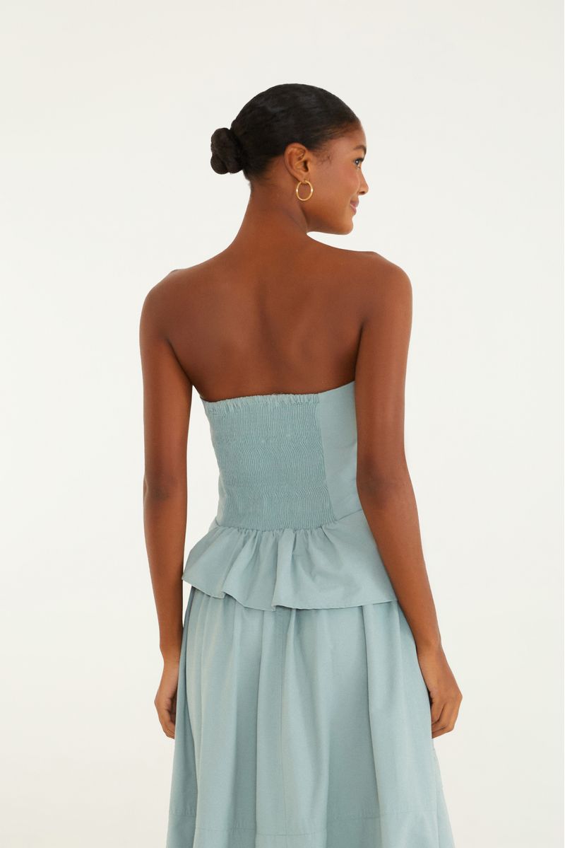 Vista lateral de la blusa con pliegues y volantes, resaltando el estilo peplum.