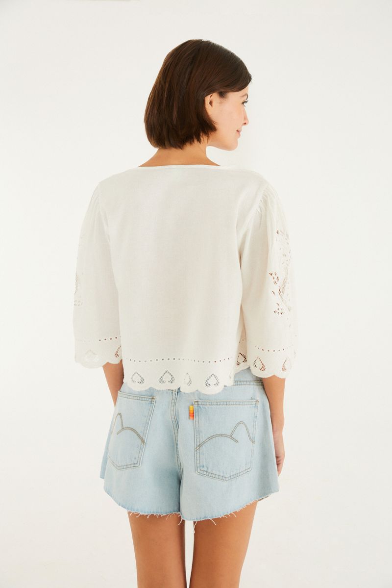 Imagen de una blusa bordada con detalles delicados, vista de cerca en el borde.