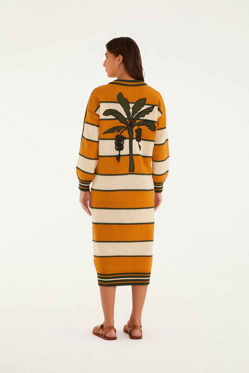 Detalle del escote en V del vestido de tejido de punto con rayas horizontales y emblema bordado.