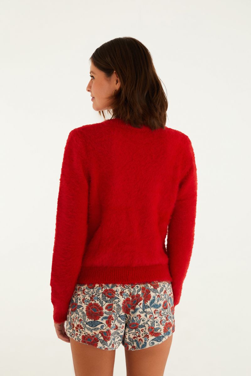 Cardigan corto de color rojo con textura de pelito, visto desde atrás, combinado con shorts estampados.