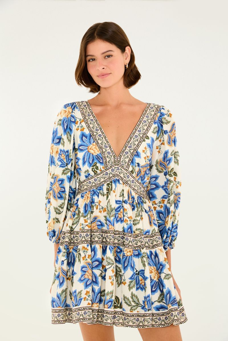 Vestido corto con estampado floral en tonos azul y amarillo, escote profundo en forma de V y mangas largas.