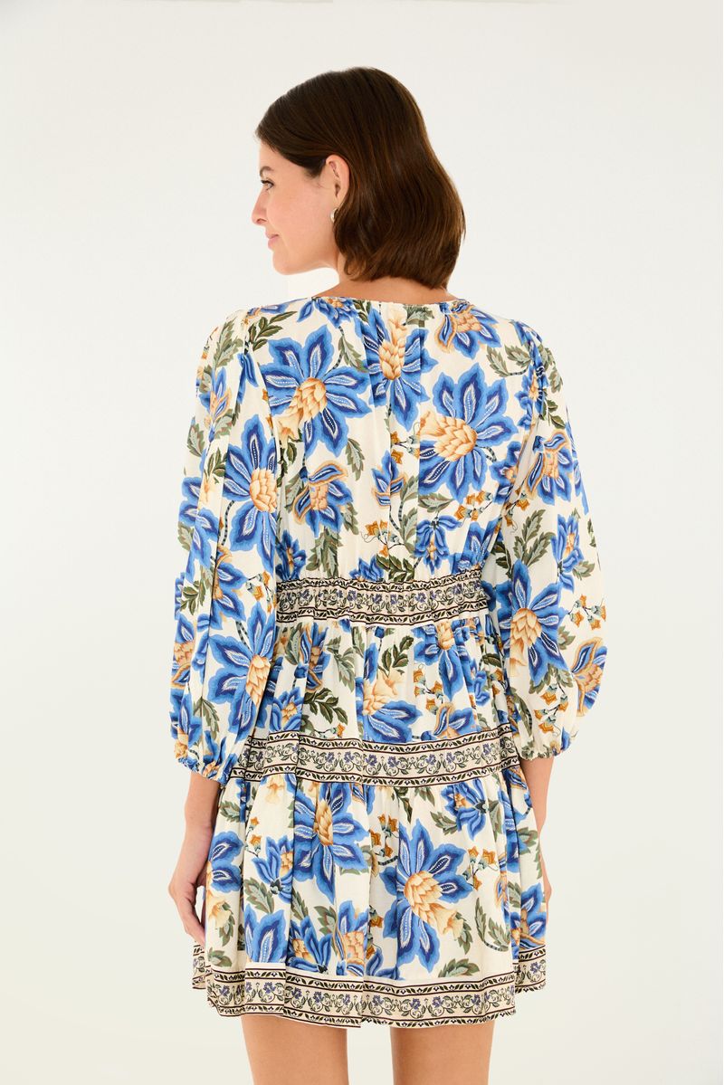 Vista trasera del vestido corto con estampado floral en tonos azul y amarillo, mangas largas y cintura definida.