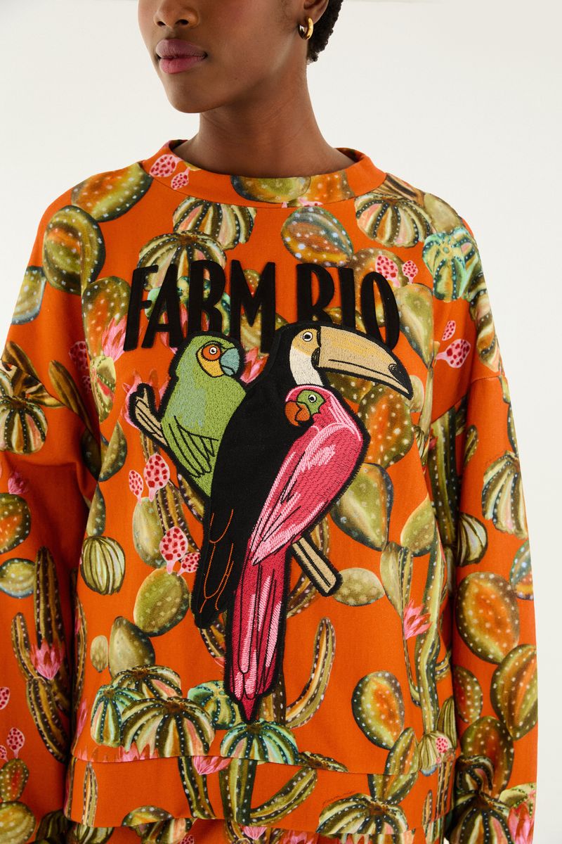 Detalle del estampado botánico en el cardigan, con aves y follaje.