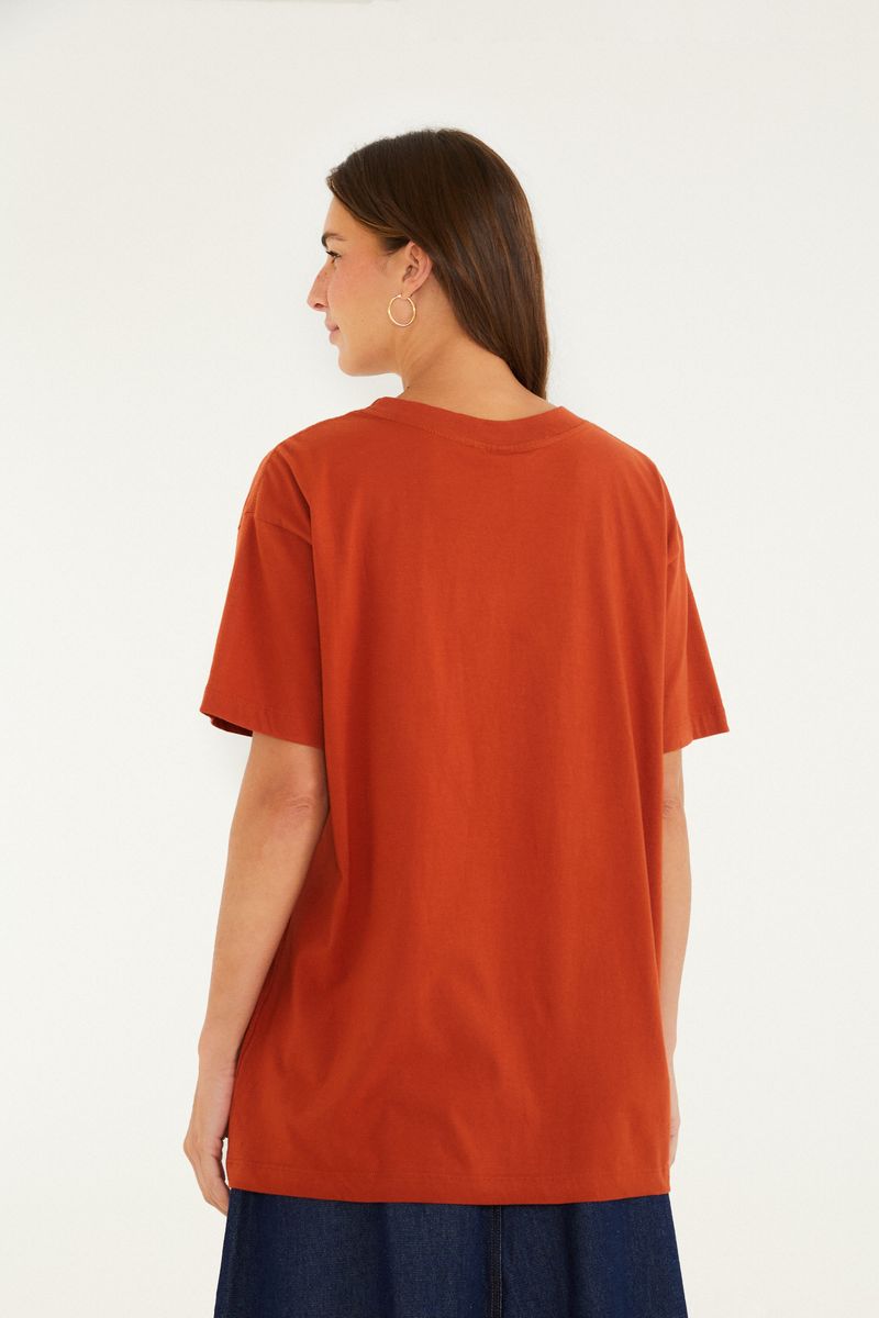 Vista trasera de la camiseta con fondo sólido terracota.