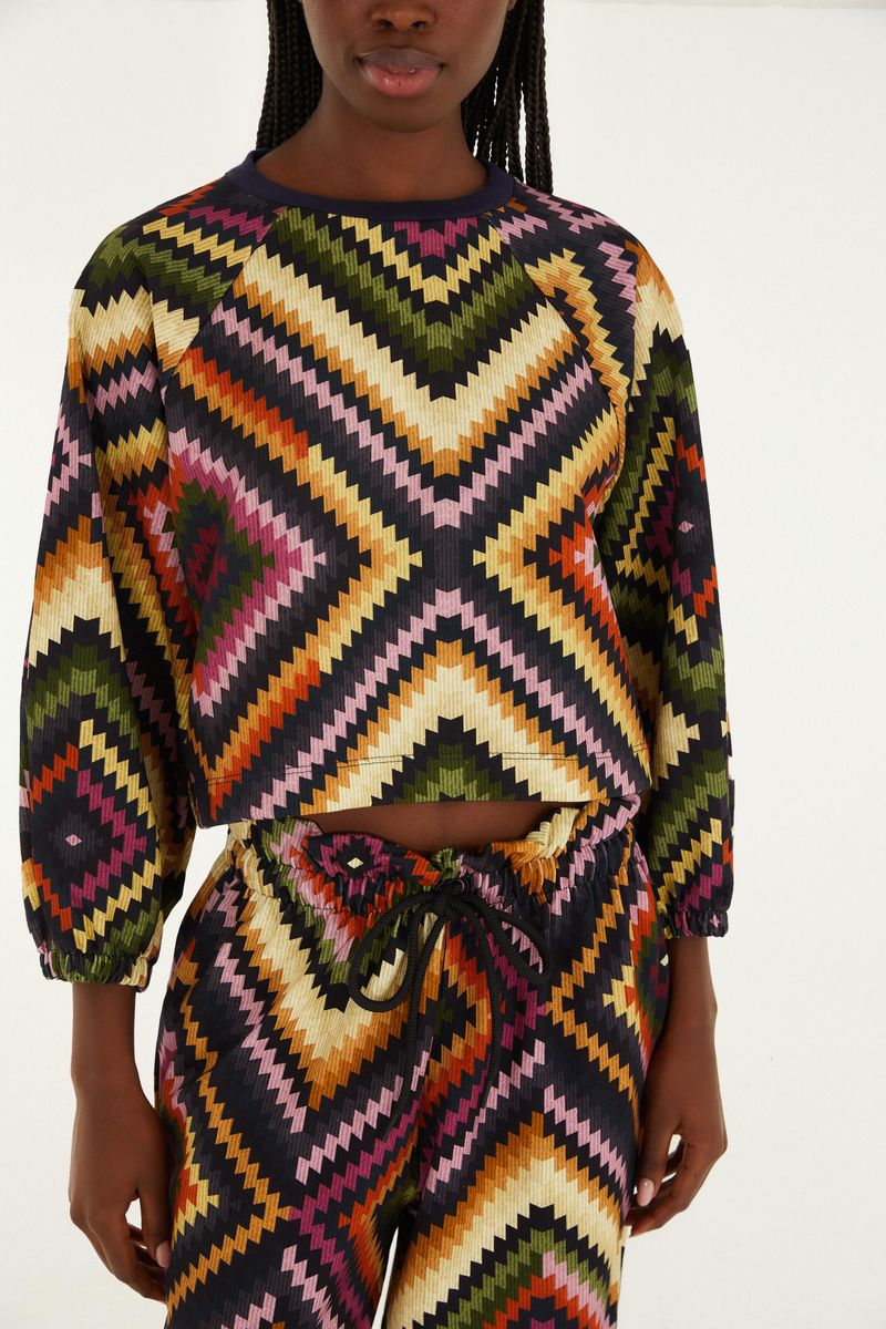 Chaqueta estilo bomber con estampado geométrico vibrante, detalle frontal.
