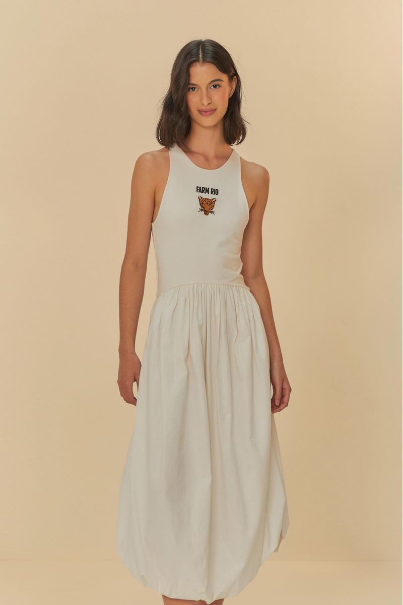 La modelo lleva el vestido blanco con bordado de tigre, sosteniendo una bolsa estampada.