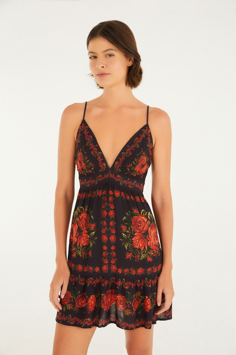 Imagen de un vestido con tirantes finos y estampado floral sobre fondo negro, visto desde atrás.