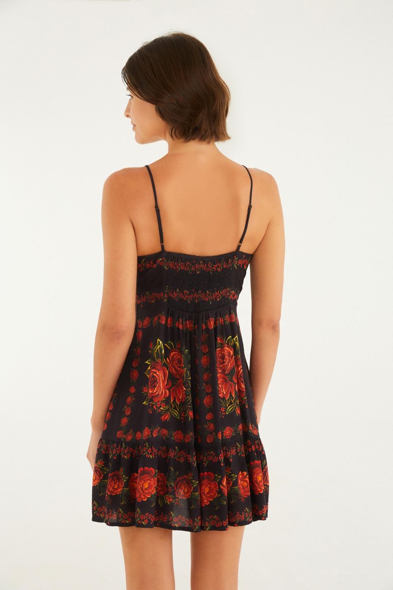 Imagen de un vestido con tirantes finos y estampado floral sobre fondo negro, mostrando detalles del escote.