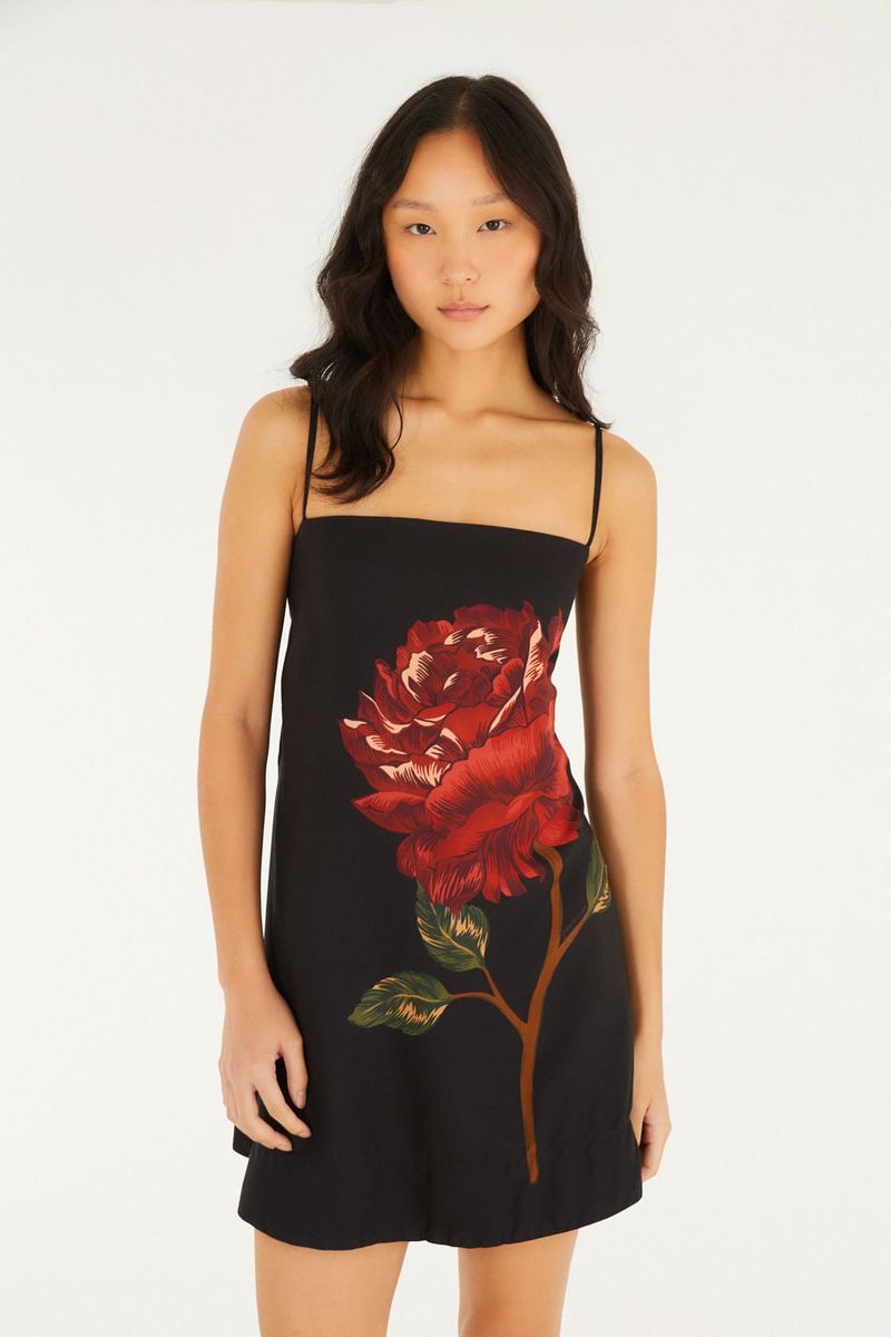 Close-up del vestido corto negro con estampado de flor roja, mostrando detalles del estampado.