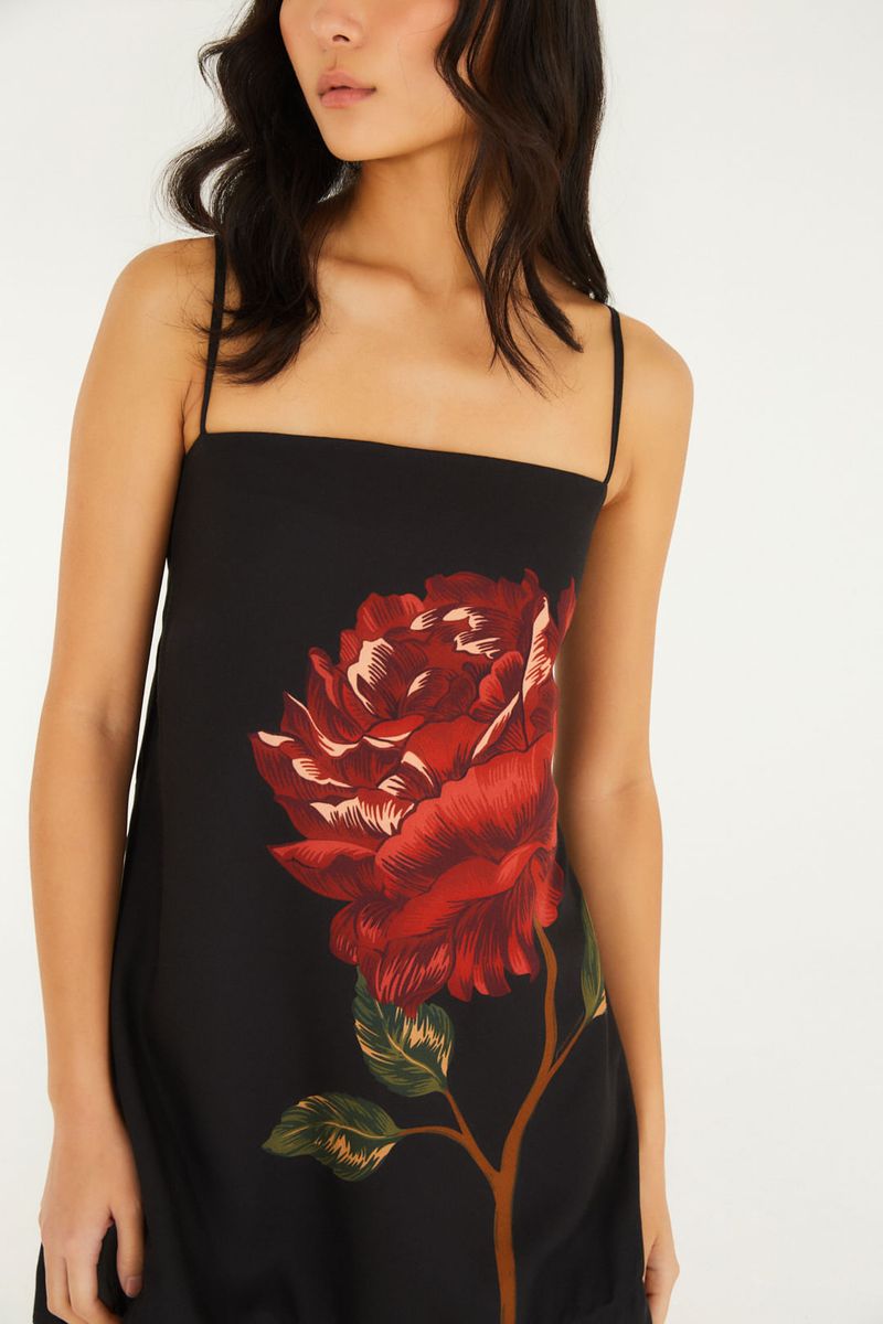 Detalle del escote del vestido corto negro con estampado de flor roja, tiras finas.