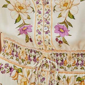 Detalle del bajo del vestido largo estampado con patrón floral y capas.