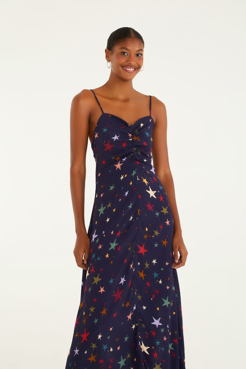 Vestido largo con tirantes y estampado de estrellas multicolores, visto de espaldas.
