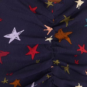 Close-up del tejido del vestido con estampado de estrellas multicolores.