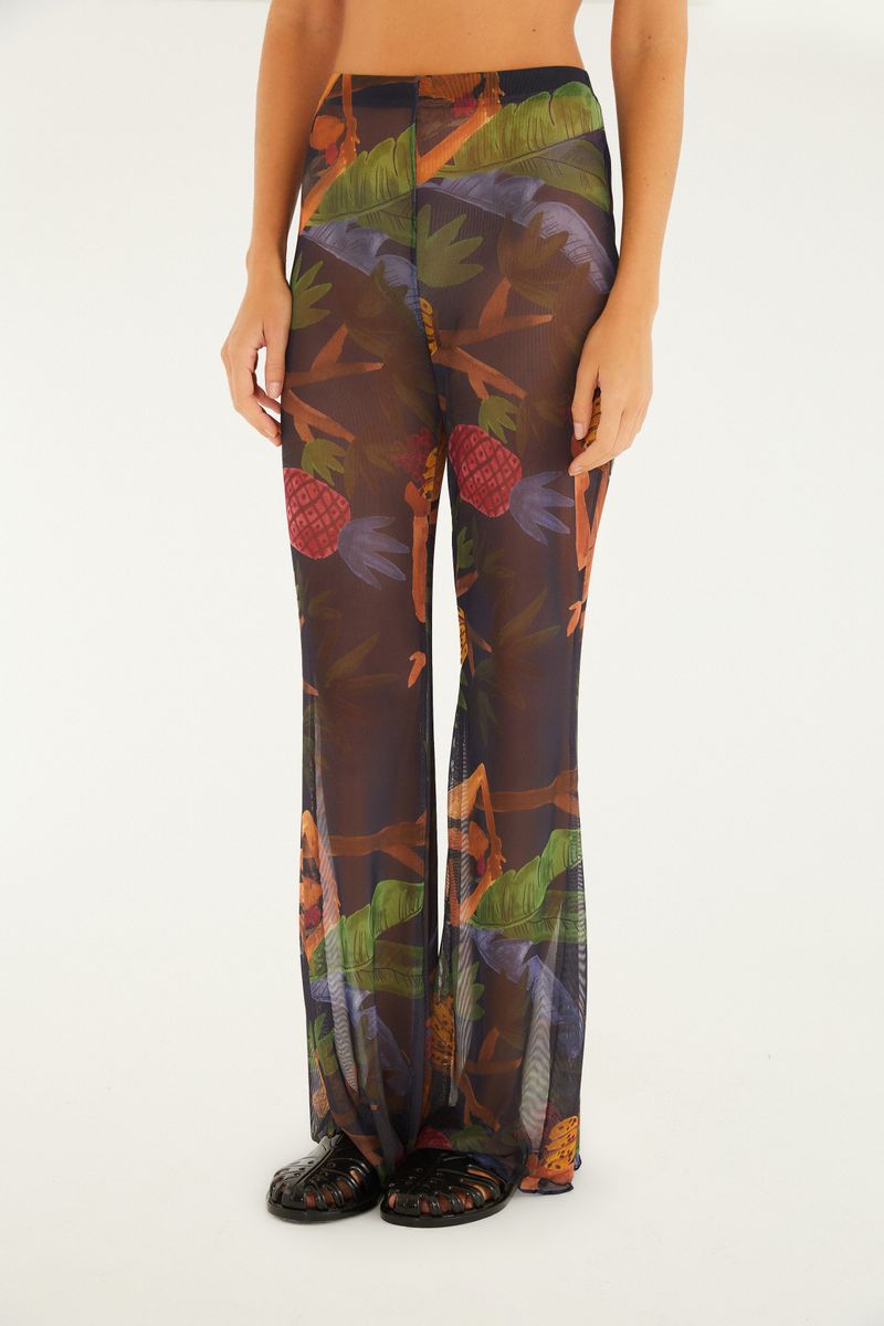 Primer plano del estampado tropical del pantalón acampanado mostrando follaje y frutas.