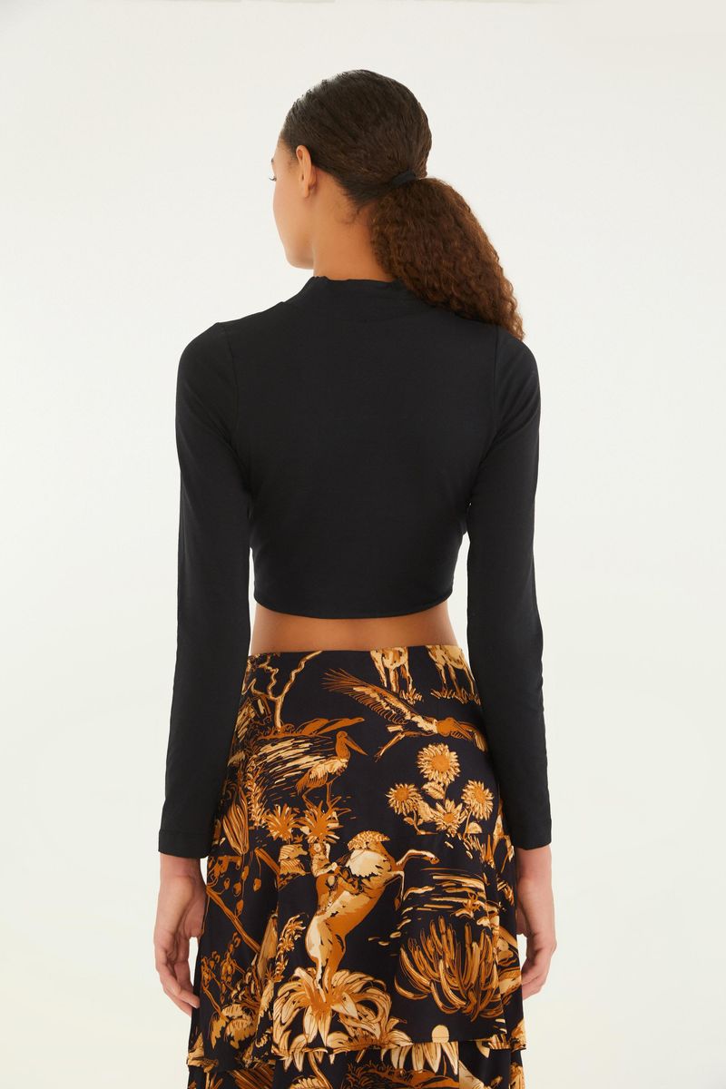 Vista trasera de la blusa cropped negra con cuello alto y mangas largas.