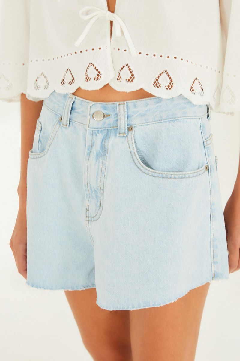 Close-up del short jeans evase azul claro mostrando detalles del cinturón y bolsillos frontales.